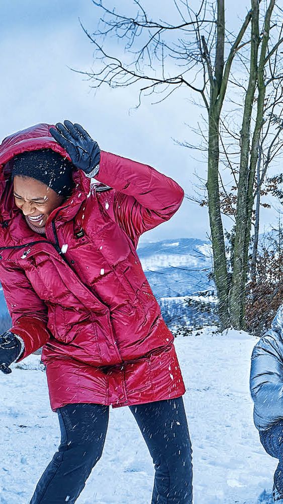 Eine Frau und zwei Männer bewerfen sich mit Schneebällen, im Hintergrund ist ein blauer Škoda zu sehen